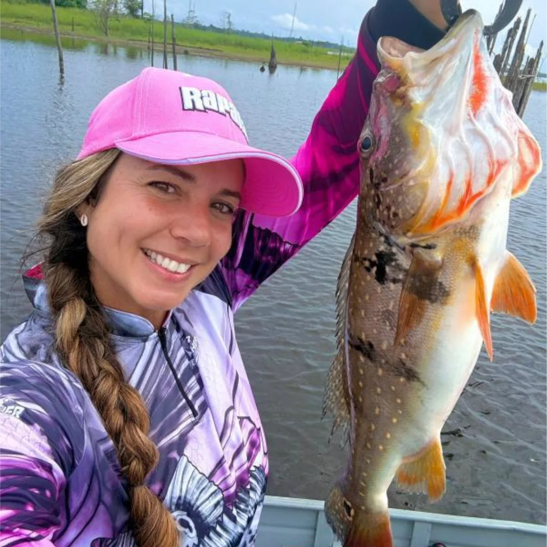 mulher pescando um grade peixe tucunaré no amazonas