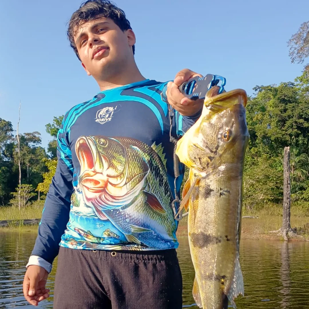 Pescador esportivo segurando um grande Tucunaré capturado na Represa de Balbina, Amazonas